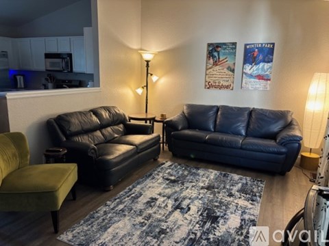 A living room with two black leather sofas and a yellow chair.