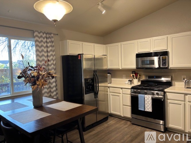 A kitchen with white cabinets and a black refrigerator.