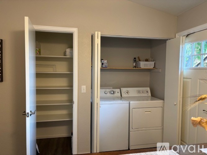 A laundry room with a washer and dryer and a cabinet with shelves.