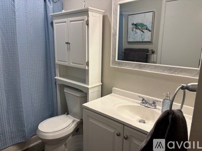 A bathroom with a toilet, sink, and a cabinet with a mirror above it.