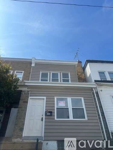 A house with a grey facade and a white door is for sale.