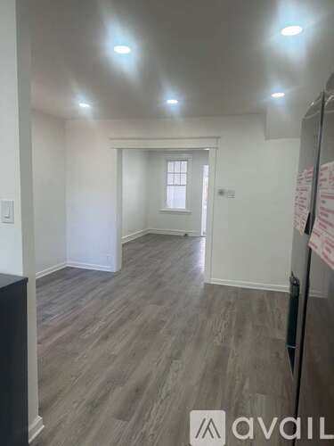 A room with wooden flooring and a refrigerator in it.