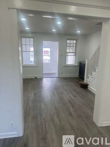 A spacious room with wood flooring and white walls.