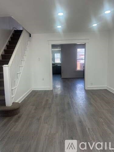A spacious room with wooden flooring and a staircase leading to the upper level.