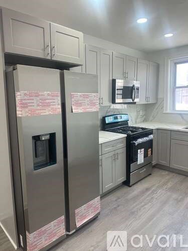 A kitchen with a stainless steel refrigerator and a black stove top oven.