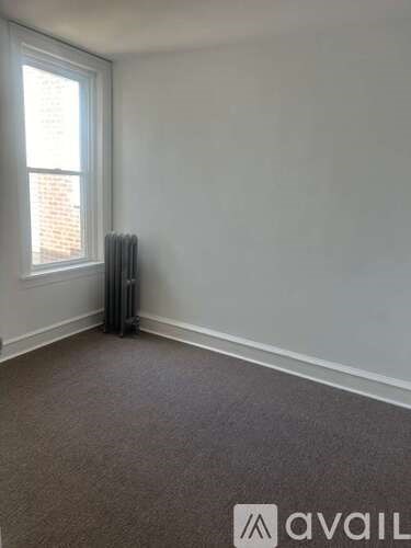 A room with a carpeted floor and a window with blinds.