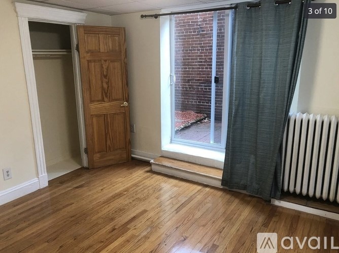 A room with a wooden door and a window with a view of a brick building outside.