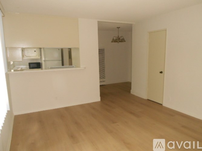 A room with wooden floors and white walls, with a window and a door.