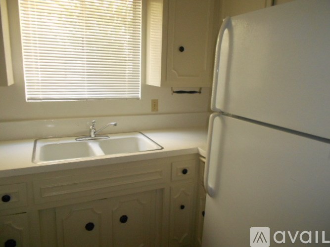 A white refrigerator stands next to a sink in a kitchen.