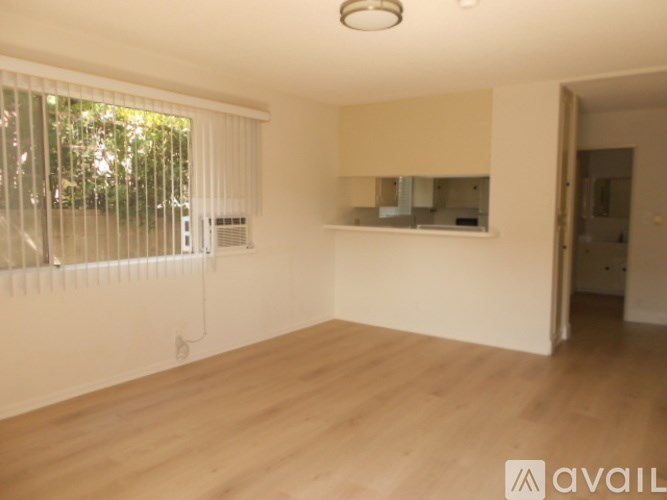 A room with wooden flooring and a window with blinds.
