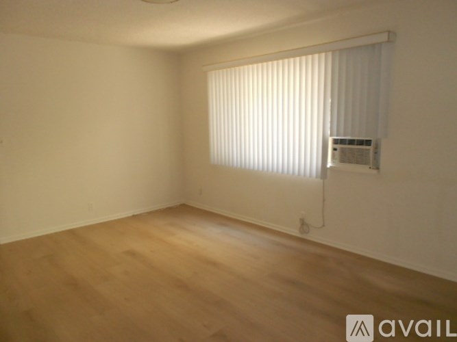A room with wooden flooring and a window with blinds.