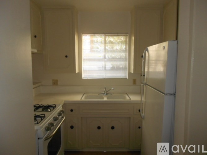 A kitchen with a stove, sink, and refrigerator.