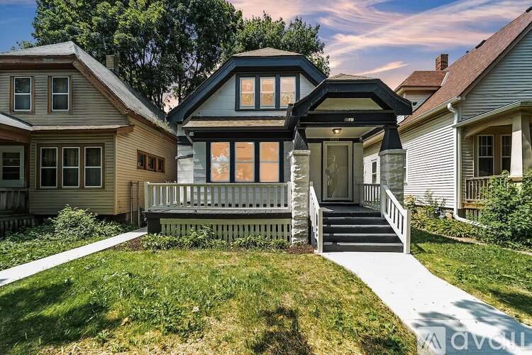 A house with a black roof and a porch with a white railing.