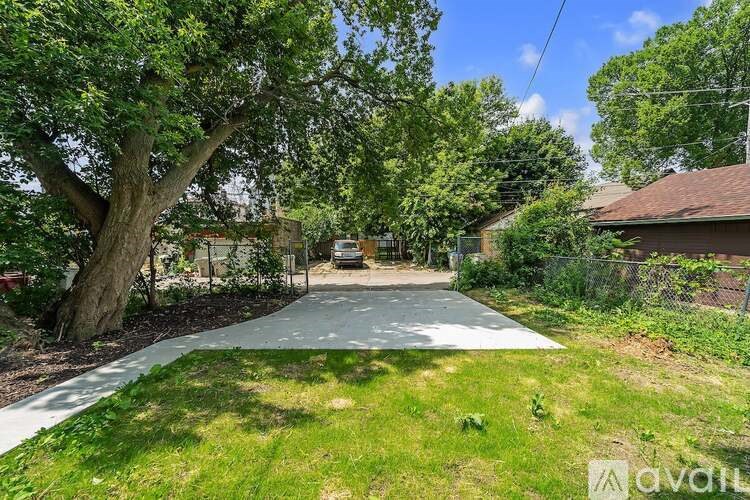 A tree-lined driveway leads to a house with a car parked in front.