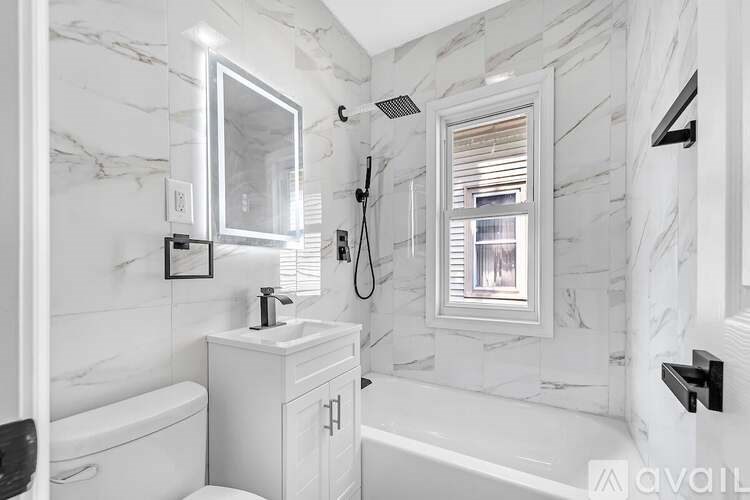 A white bathroom with marble walls and a tub.