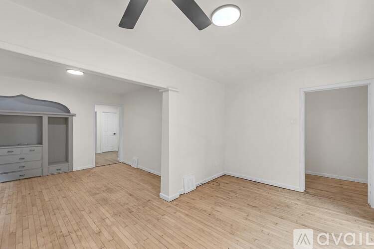 A room with a ceiling fan and wooden flooring.