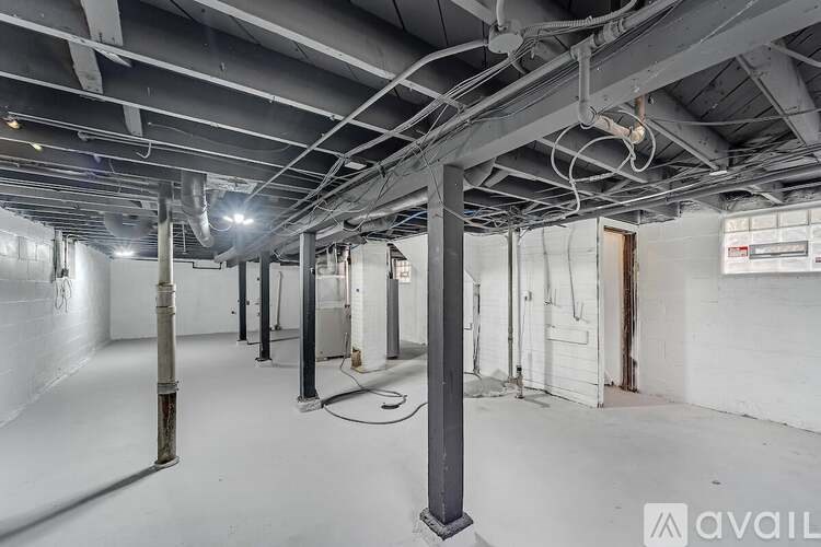 A large empty industrial space with white walls and a concrete floor.