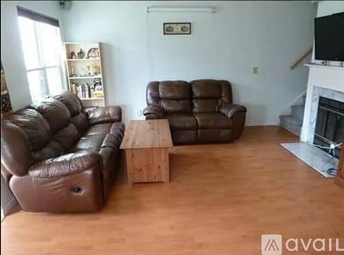 A living room with brown leather furniture and a fireplace.
