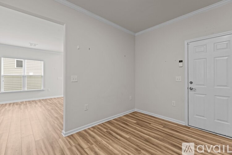 A room with a white door and wooden flooring.