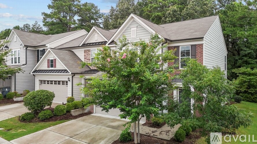 A house with a garage and a tree in front of it.