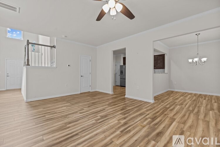 A spacious room with wooden flooring and a ceiling fan.