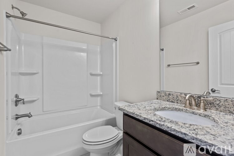 A white bathroom with a marble countertop and a glass shower enclosure.