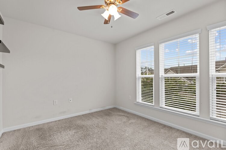 A room with a ceiling fan and carpeted floor.