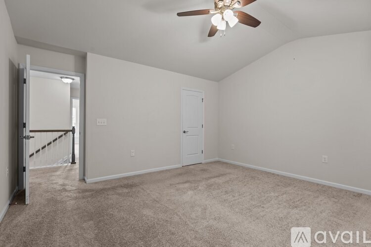 A room with a ceiling fan and carpeted floor.
