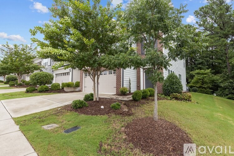 A tree in a mulched area in front of a house.