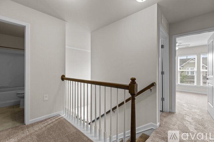 A room with a carpeted floor and a staircase with a wooden railing.