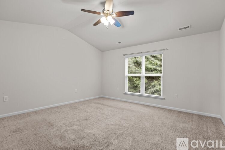 A room with a ceiling fan and a window with blinds.