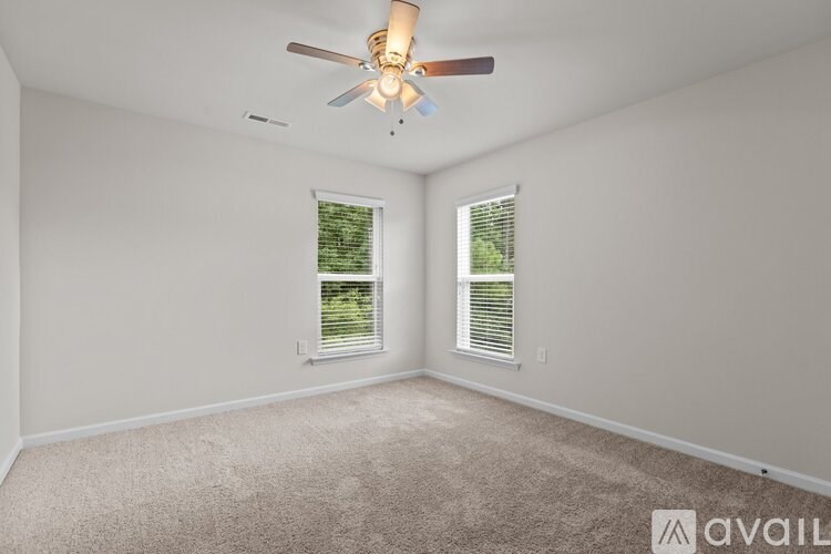 A room with a ceiling fan and two windows.