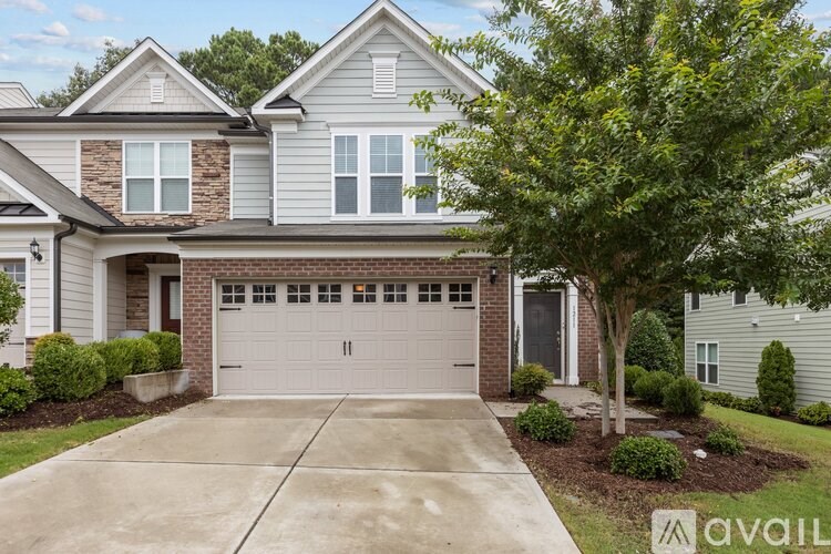A house with a garage and a tree in front.