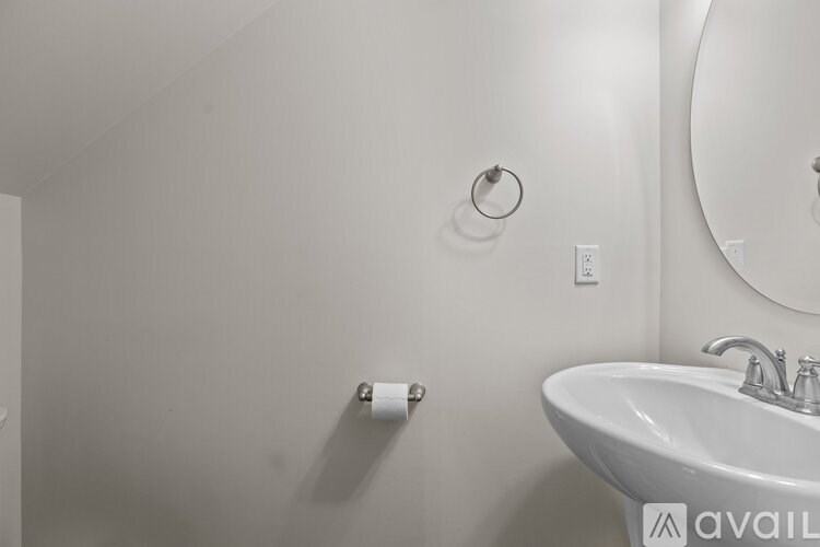 A bathroom with a sink, mirror, and toilet paper holder.