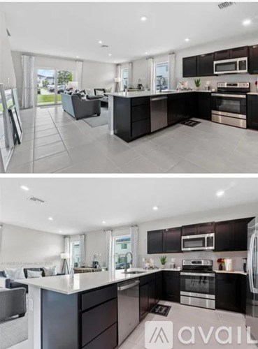A modern kitchen with black cabinets and stainless steel appliances.