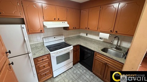 A kitchen with brown cabinets and a white fridge.
