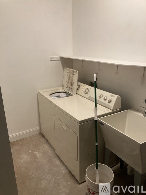 A bathroom with a toilet, sink, and a mop.