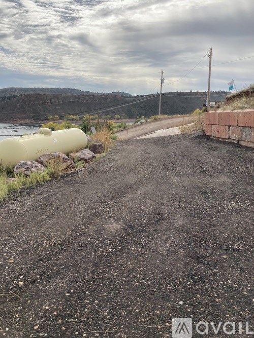 A gravel road leads to a body of water with a cloudy sky above.