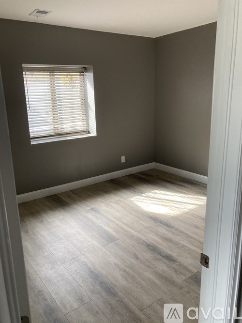 A room with a window and wooden flooring.