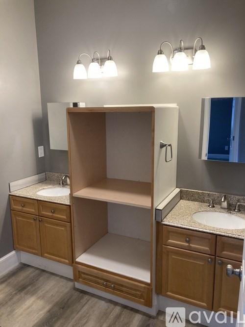 A bathroom with a double sink vanity and a large open medicine cabinet.