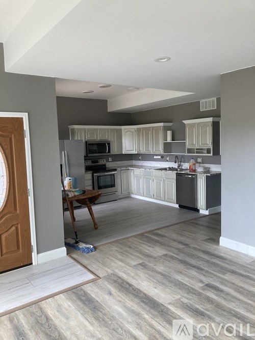 A kitchen with a wooden floor and a brown door.