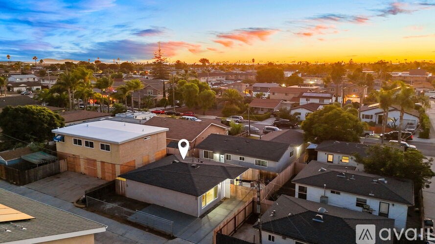 A sunset view of a neighborhood with a house for sale.