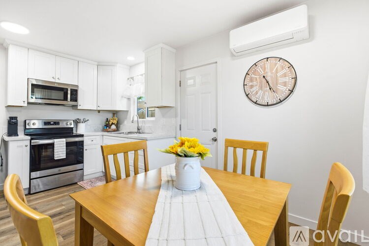 A kitchen with a table set for four with yellow flowers in the middle.