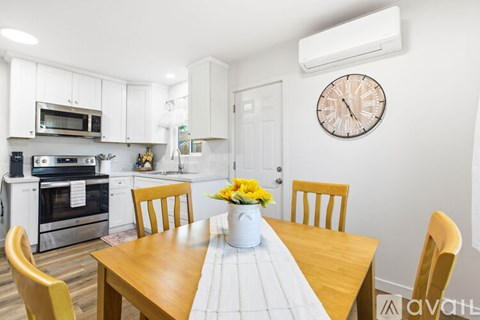 A kitchen with a table set for four with yellow flowers in the middle.