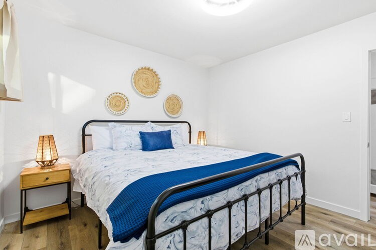 A bedroom with a bed, nightstand, and wall decor.