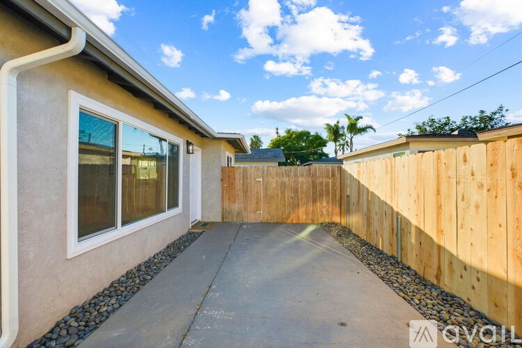 A house with a wooden fence and a concrete pathway leading to the front door.