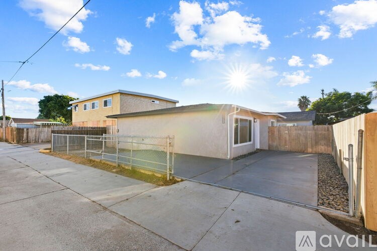 A sunny day with a house and a fenced yard.