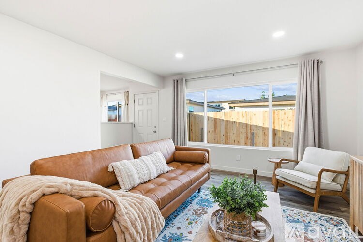 A living room with a brown leather couch and a white chair.