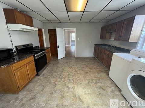A kitchen with a black stove top oven and a washing machine.