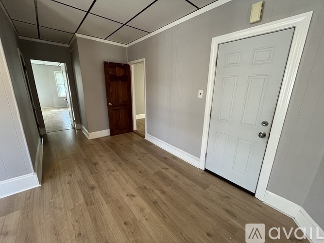 A room with a white door and wooden flooring.